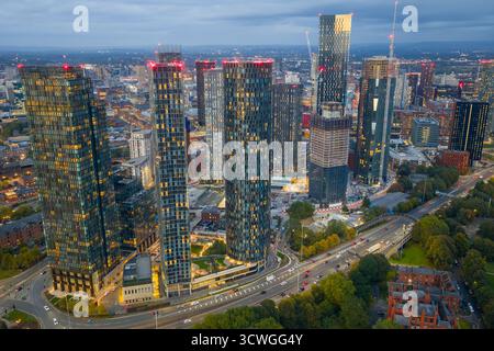 Immagine aerea al crepuscolo dello skyline di Manchester con grattacieli illuminati e la via mancuniana sottostante. Foto Stock
