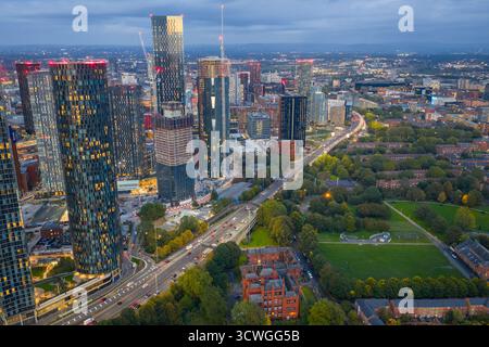 Immagine aerea al crepuscolo dello skyline di Manchester con grattacieli illuminati e la via mancuniana sottostante. Foto Stock