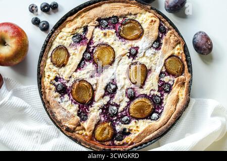 Torta, quiche o cheesecake con formaggio fresco, mirtilli e prugne. Una colazione deliziosa e bella. Vista dall'alto. Foto di alta qualità Foto Stock