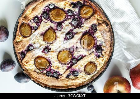 Torta, quiche o cheesecake con formaggio fresco, mirtilli e prugne. Una colazione deliziosa e bella. Vista dall'alto. Foto di alta qualità Foto Stock