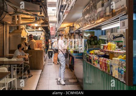 Bangkok, Tailandia - 22 gennaio 2025: Un vivace mercato di strada caratterizzato da bancarelle colorate di frutta e verdura e acquirenti che acquistano cibo. Foto Stock