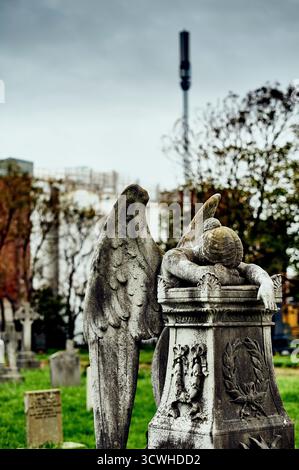 Statua dell'angelo che piange sulla ghiaia e sul montante del telefono cellulare sullo sfondo, Regno Unito Foto Stock
