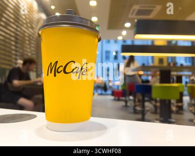 Poznan, Polonia - 11 settembre 2025: L'importante tazza di caffè usa e getta gialla McCafe si erge su un elegante bancone bianco, mostrando il marchio all'interno di un vibr Foto Stock