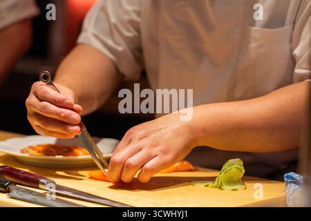 Lo chef esperto prepara sushi con ingredienti freschi su un ripiano in legno, mostrando esperienza culinaria e attenzione ai dettagli. Foto Stock