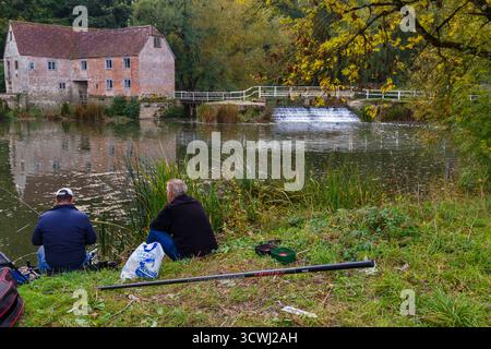 Sturminster Newton, Dorset, Regno Unito. 12 ottobre 2025. Meteo nel Regno Unito: Colori autunnali a Sturminster Newton Mill, Dorset. Sturminster Newton Mill è uno dei pochi mulini rimasti sul fiume Stour, parte di una serie di antichi mulini costruiti sul fiume. Si tratta di un mulino ad acqua completamente funzionante che produce farina, venduto nei negozi del Museo e del Mulino ed è un meraviglioso pezzo di archeologia industriale. Pescatori che pescano lungo le rive. Crediti: Carolyn Jenkins/Alamy Live News Foto Stock