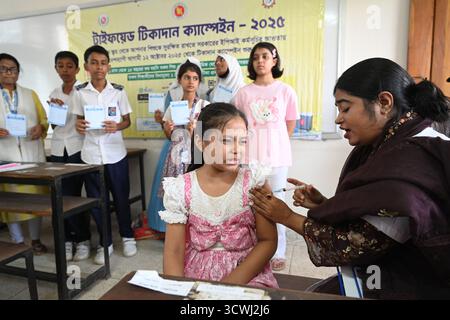 Uno studente riceve un vaccino contro il tifo in un centro di vaccinazione scolastico durante una campagna di vaccinazione nazionale a Dacca, Bangladesh, il 12 ottobre 2025. Per la prima volta, il governo ha iniziato a somministrare la vaccinazione contro il tifo in tutto il paese. Circa 50 milioni di bambini di età compresa tra 9 mesi e 15 anni riceveranno il vaccino gratuitamente in 18 giorni lavorativi. I primi 10 giorni lavorativi saranno concessi in varie scuole, mentre i prossimi otto giorni lavorativi saranno assegnati nei centri di vaccinazione. Foto Stock