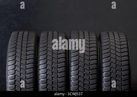 Primo piano degli pneumatici su sfondo nero. Pneumatici per auto, ruote invernali isolate Foto Stock