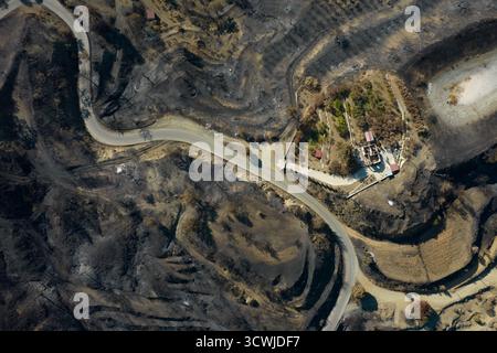 Il terreno arroccato mostra le conseguenze di un devastante incendio selvatico che ha spazzato attraverso la foresta, lasciando alberi carbonizzati e terreno annerito in un luogo remoto Foto Stock
