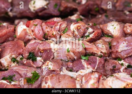 Pezzi di filetto di maiale crudo preparati su spiedini, pronti per la frittura. Foto Stock