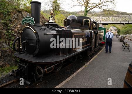 Storica locomotiva a vapore sulla piattaforma della stazione ferroviaria rurale con guardia in uniforme Foto Stock