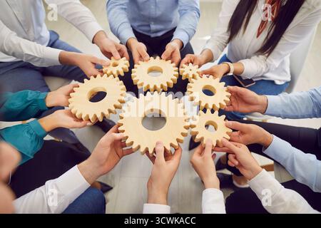 Mani di uomini d'affari che collegano grandi ingranaggi, primi piani Foto Stock