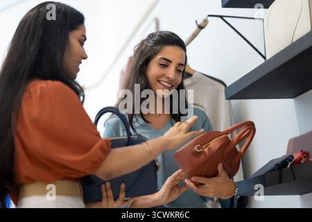 Giovane assistente alle vendite indiano che fornisce supporto alla donna cliente Foto Stock