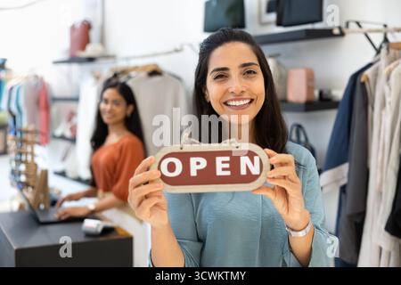 Felice, giovane e giovane manager latino che tiene in mano il cartello aperto Foto Stock