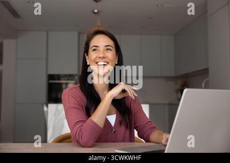 Bella donna latina felice che scrive sul laptop a casa Foto Stock