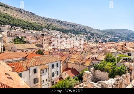 Vista sopraelevata sui tetti in terracotta della città vecchia di Dubrovnik, con il monte Srđ che sorge sullo sfondo sotto la luce dell'estate. Foto Stock
