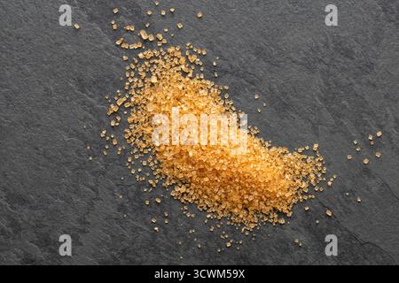 Saccharum officinarum - zucchero granulato marrone sparso sulla tavola Foto Stock