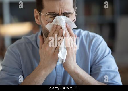 Ritratto di primo piano uomo malato che copre la bocca del naso con un tovagliolo di carta Foto Stock