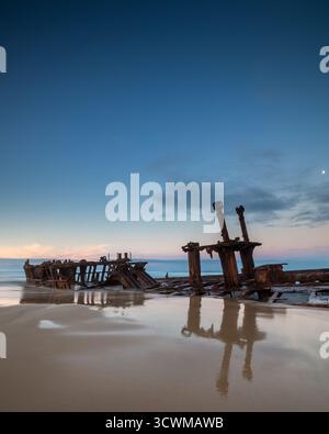 Resti arrugginiti del naufragio della nave a vapore Maheno a K'gari (isola Fraser), Australia. Parzialmente sommerso nella sabbia e in acque poco profonde, corroso Foto Stock