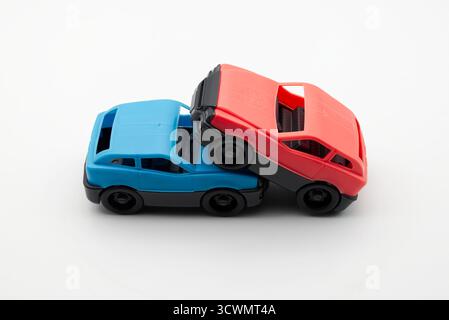 Due colorate macchinine di plastica che simulano un incidente stradale con un veicolo rovesciato in bianco. Foto Stock