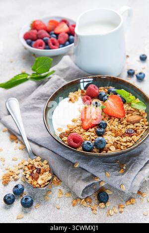Ciotole di muesli con fragole fresche, mirtilli, lamponi, yogurt, noci, e miele per una colazione sana Foto Stock