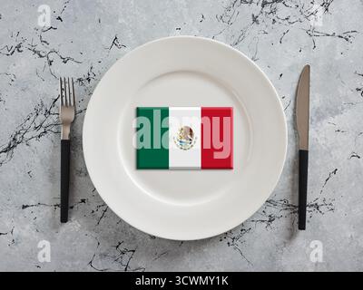 Bandiera messicana posta su un piatto bianco con forchetta e coltello, che rappresenta la cucina e la cultura messicana Foto Stock