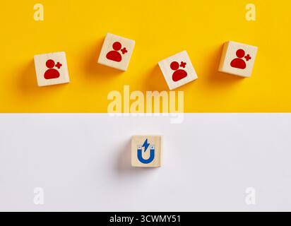 Cubi di legno con icone e magnete che li attrae, che rappresentano l'attrazione di clienti e lead Foto Stock