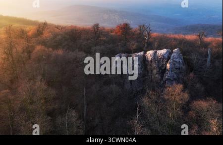 Splendido tramonto, foreste autunnali, rocce e colline sullo sfondo. Drone aereo Foto Stock