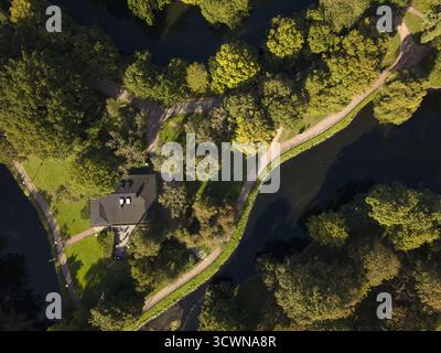 Vista aerea di un tranquillo canale che si snoda attraverso la lussureggiante tettoia di Kungsparken, riflettendo le sfumature del cielo tra il vivace fogliame verde di Malmo, Svezia. Foto Stock