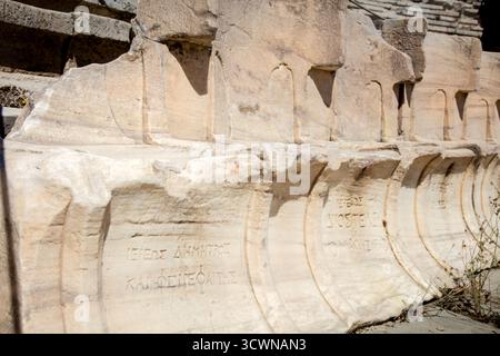 Antiche iscrizioni greche alla base di Profedria, sedili in pietra pentelica/troni d'onore, nel Teatro di Dioniso sull'Acropoli, Atene, Greec Foto Stock