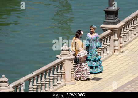 Siviglia, Spagna - 23 apr 23: Due donne in abiti colorati tradizionali in piedi sul lungomare Foto Stock