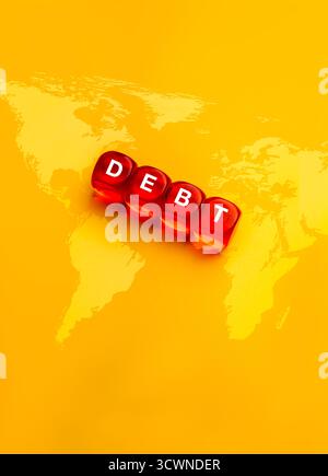 Dadi rossi con DEBITO di parole sullo sfondo della mappa mondiale in giallo. Concetto di crisi globale del debito, onere finanziario, questione economica, credito internazionale Foto Stock