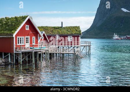 Tradizionale cabina rossa da pesca (rorbu) su palafitte sulle limpide acque turchesi nel villaggio di Reine, isole Lofoten, Norvegia. Foto Stock