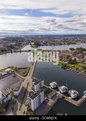 Vista aerea degli edifici moderni che incontrano le acque tranquille, i ponti collegano la città vecchia alla nuova, sotto un vasto cielo punteggiato di nuvole, Kalmar, Kalmar County Foto Stock