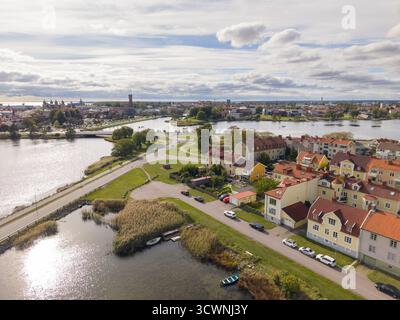 Vista aerea degli edifici dal tetto dorato annidati accanto all'acqua scintillante, dove la vecchia torre dell'acqua si erge all'orizzonte, Kalmar, Kalmar County Foto Stock