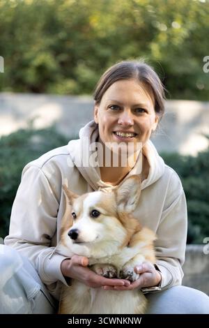 Ritratto femminile con un corgi Pembroke, donna sorridente con cane Foto Stock