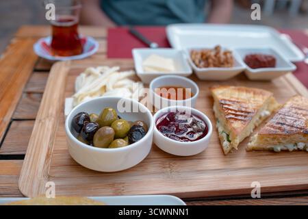 Colazione tradizionale turca con pane fresco, olive, formaggio, pomodori, cetrioli, e varietà di inceppamenti e spalmazioni. Godibile in un ambiente vivace Foto Stock