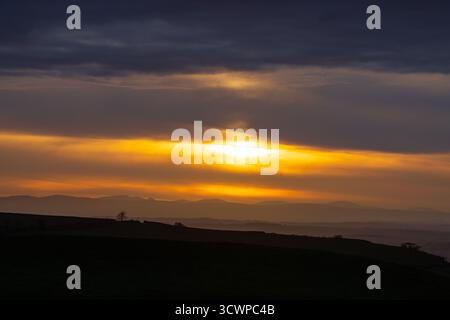 Il sole tramonta sulle montagne del Lake District e si affaccia sulla valle dell'eden. Cumbria, Inghilterra, Regno Unito. Foto Stock
