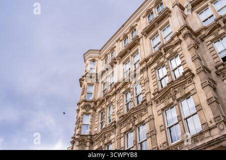 Storico ed elegante edificio di appartamenti a più piani con facciata ornata e alte finestre, adagiato su un cielo nuvoloso. Edificio vecchio, urbano e vintage Foto Stock