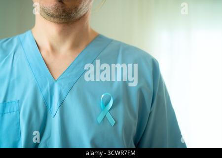 Medico in abbigliamento medico con nastro blu sul petto che simboleggia novembre consapevolezza del cancro alla prostata e diagnosi precoce per cure mediche tempestive. Foto Stock