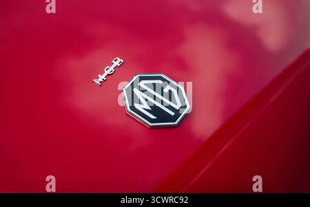 Logo MG sull'auto rossa - Vista ravvicinata. Emblema ottagonale dell'auto britannica sul bagagliaio della roadster MGB degli anni '1960. Foto Stock