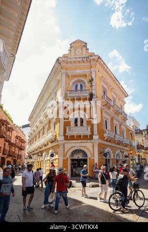 Cartagena de Indias, Colombia - 16 dicembre 2023: Edificio giallo vibrante di epoca coloniale con un'intricata architettura nell'affollata città storica fortificata Foto Stock