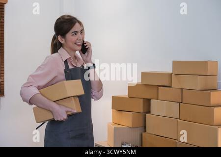Startup piccola impresa imprenditore PMI, donna asiatica ricevere ordine al telefono. Successo giovane asiatico piccola impresa proprietario home Office, vendita online Foto Stock