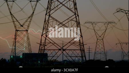 Torreggianti tralicci in acciaio, linee elettriche che si estendono attraverso il sito di servizi pubblici all'alba, con sottostazione Foto Stock