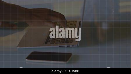 Digitazione dei tasti a mano sul laptop argento sul piano bianco dell'ufficio domestico, con smartphone nero Foto Stock