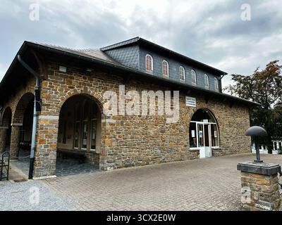 Banneux, Belgio - 20 ottobre 2023: Un edificio storico in pietra in Belgio con archi, finestre e un pittoresco ambiente plaza. Santuario di nostra Signora Foto Stock