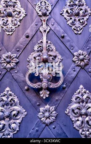 Maniglie delle porte in ferro battuto ornate e lavorazione floreale in metallo su una storica porta in legno a Praga che mostra l'artigianato gotico e barocco Foto Stock