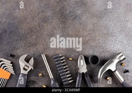Set di pinze per utensili manuali, chiave, martello, punte per cacciaviti sparse su sfondo grigio. Vista dall'alto. Foto Stock
