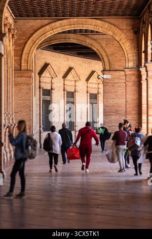 Dopo l'arrivo di un'auto della polizia, i venditori ambulanti fuggono da Plaza de España mentre i turisti fanno fotografie a Siviglia, in Spagna. Foto Stock