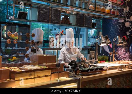 Lo chef lavora alla postazione uova al bar della colazione nell'hotel di lusso Shangri-la, a Chengdu, Cina. Foto Stock