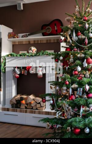 L'albero di Natale nel soggiorno è decorato in rosso e bianco con ornamenti di alberi di Natale in carta a nido d'ape. Sullo sfondo c'è un Fi elettrico Foto Stock